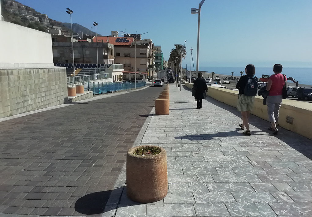 Un tratto della passeggiata. Una serie di vasi separa la zona pedonale da quella carrozzabile. Un muretto corre lungo tutto l'altro lato del marciapiede.