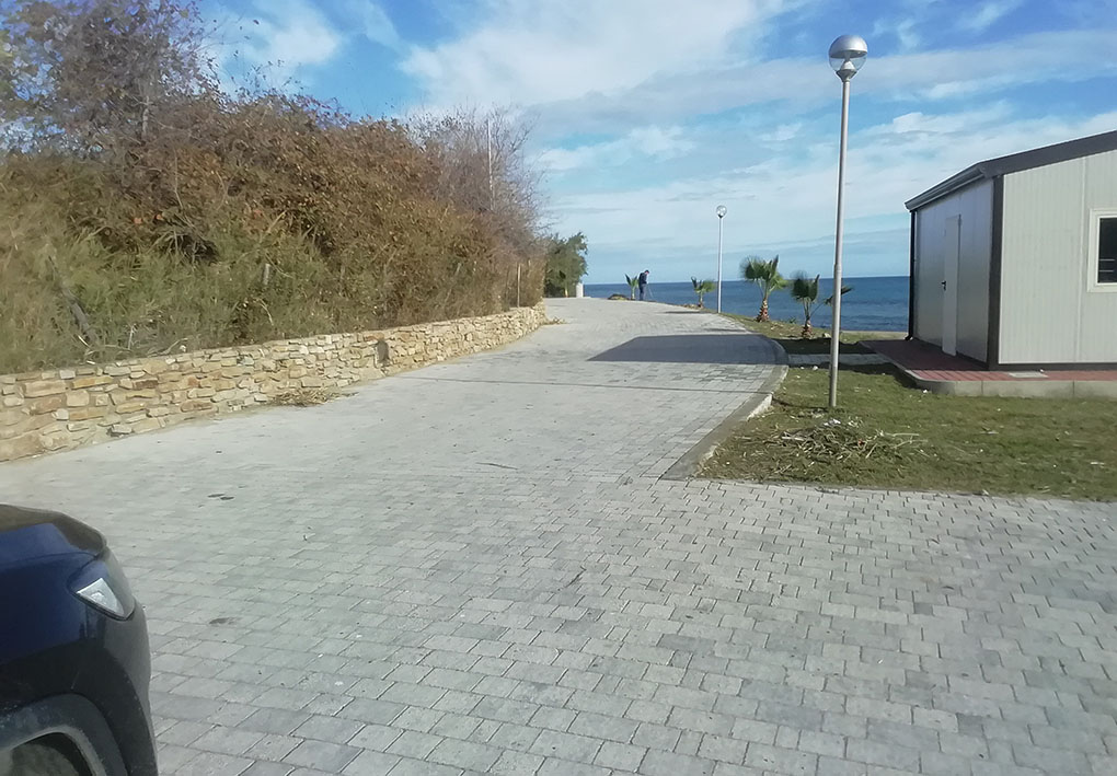 Imbocco di una larga strada lastricata in riva al mare.