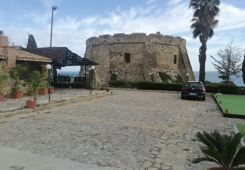 un ampio piazzale in riva al mare con parcheggio. Poco oltre la strada sorge la rocca.