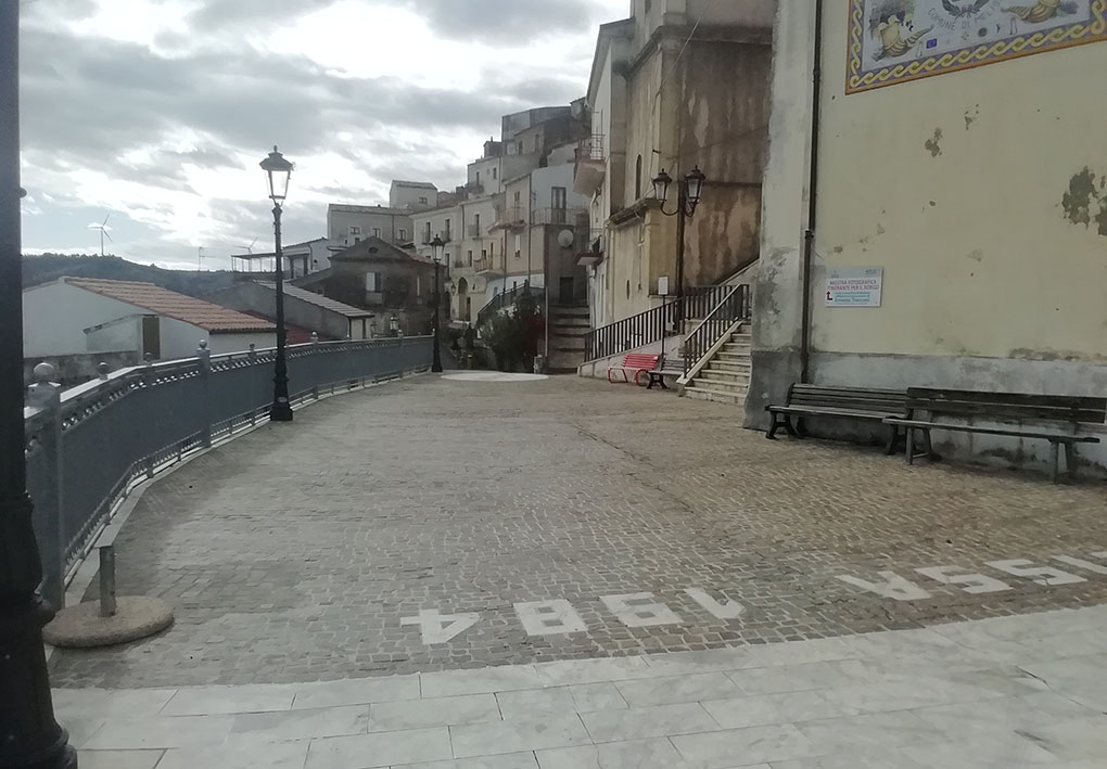 Ampia strada lastricata lungo il centro storico. A monte si trova una serie di palazzi, dall'altro lato una ringhiera.