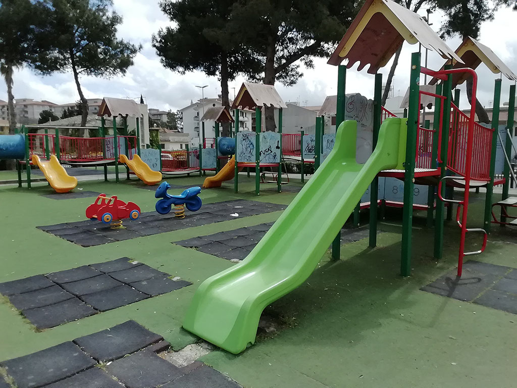 scivoli e giochi per bambini in un'area gioco con pavimento gommato