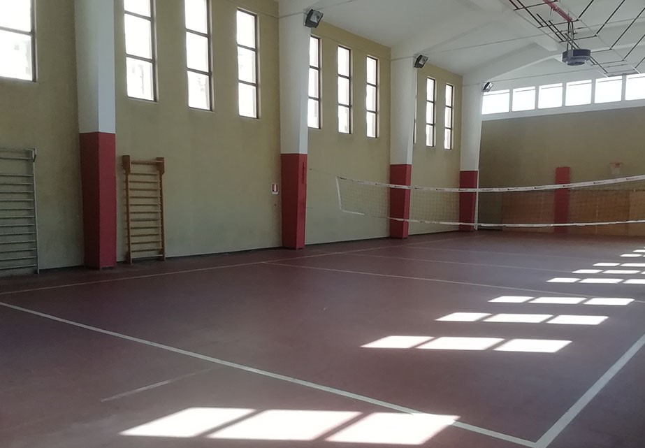 un palazzetto sportivo interno, con una rete da pallavolo montata e attrezzi sui muri laterali