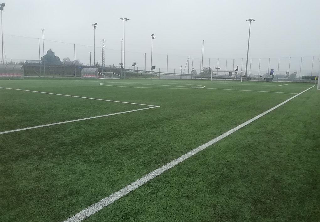 Un campo da calcio a 11 in erba sintetica, contornato da reti