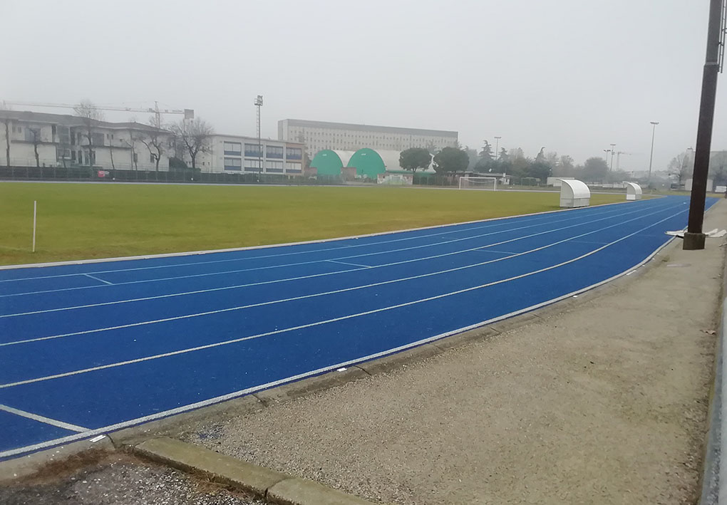 Campo in erba con intorno una pista di atletica. In lontananza si notano altre strutture sportive