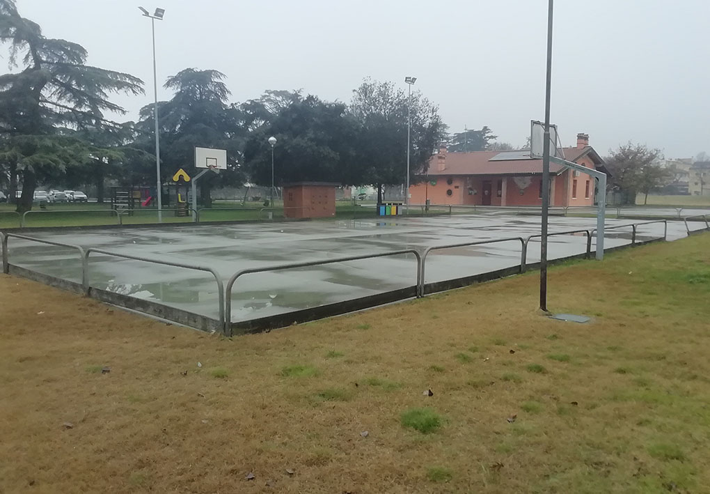 Un campo da basket a filo del parco, protetto da ringhiere di metallo