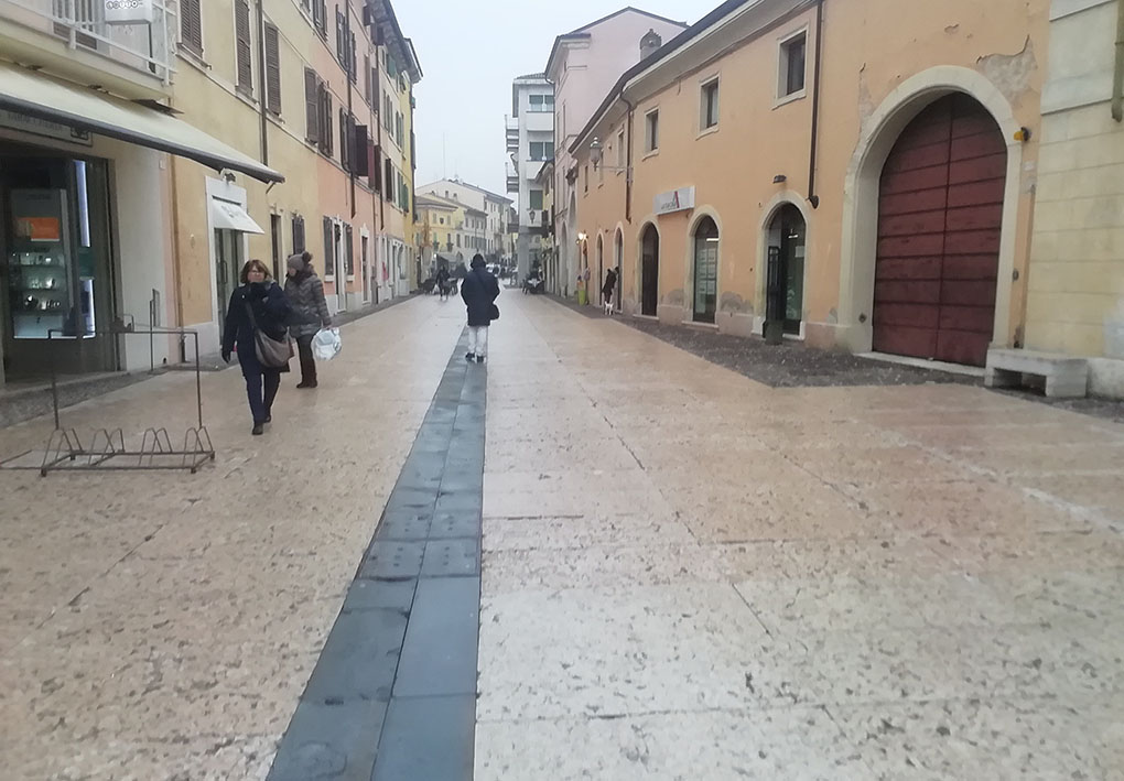 Una stada lastricata del centro pedonale, tra bassi palazzi e botteghe storiche