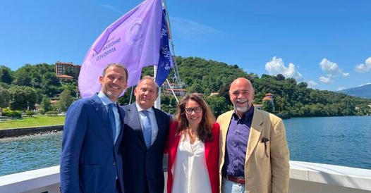 Rappresentanti di Navigazione Laghi posano davanti alla bandiera lilla insieme al ministro Alessandra Locatelli e al presidente di Bandiera Lilla Roberto Bazzano